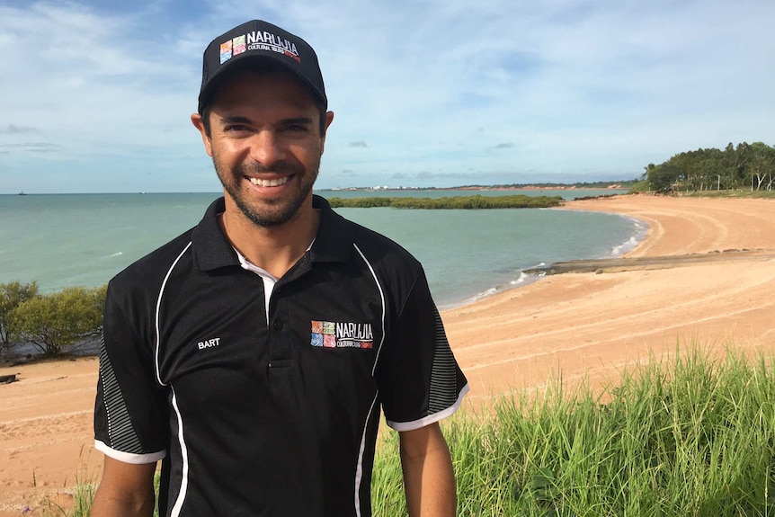 Bart Pigram standing on bank with sand and ocean behind.