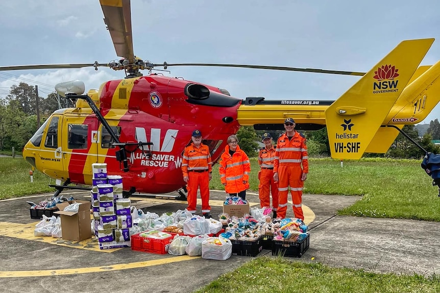 people smiling in front of a helicopter with food supplies