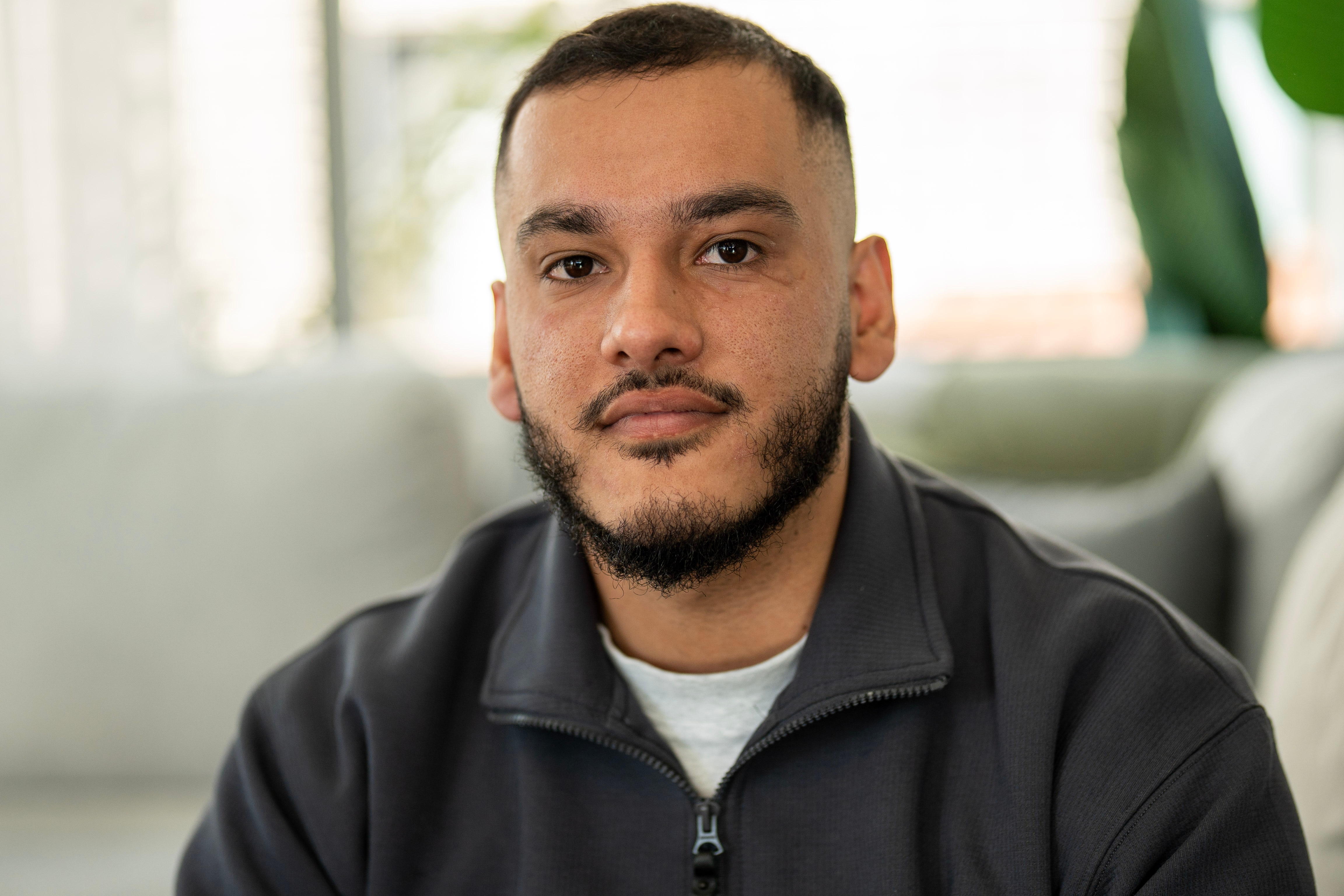 Man with dark black hair looking at camera, wearing hoodie