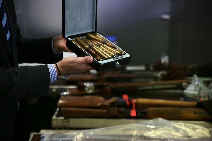 A police detective holds a box of gold coloured ammunition rounds.