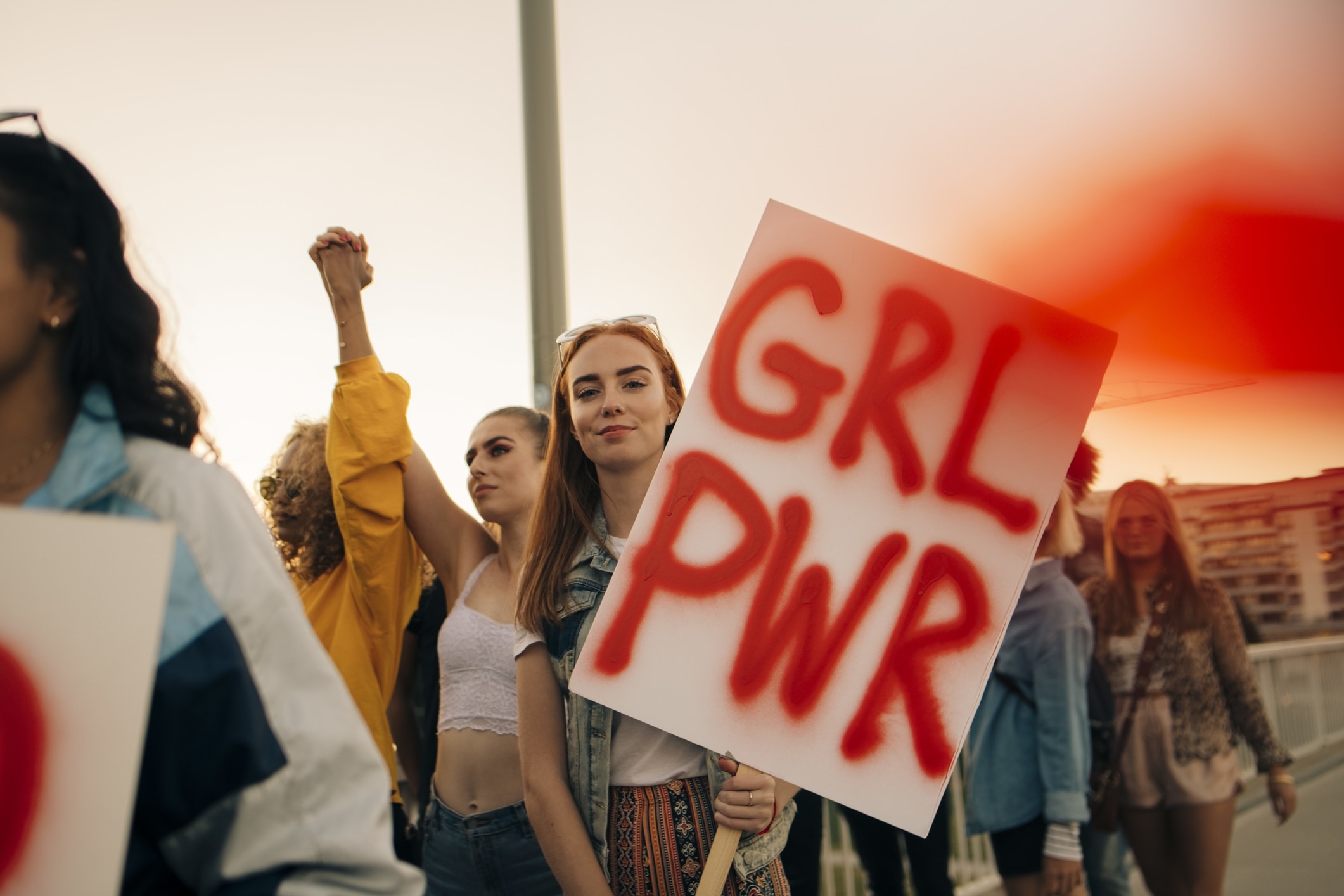 A woman in a crowd of other women holding a placard with the words sprayed in red "GRL PWR"