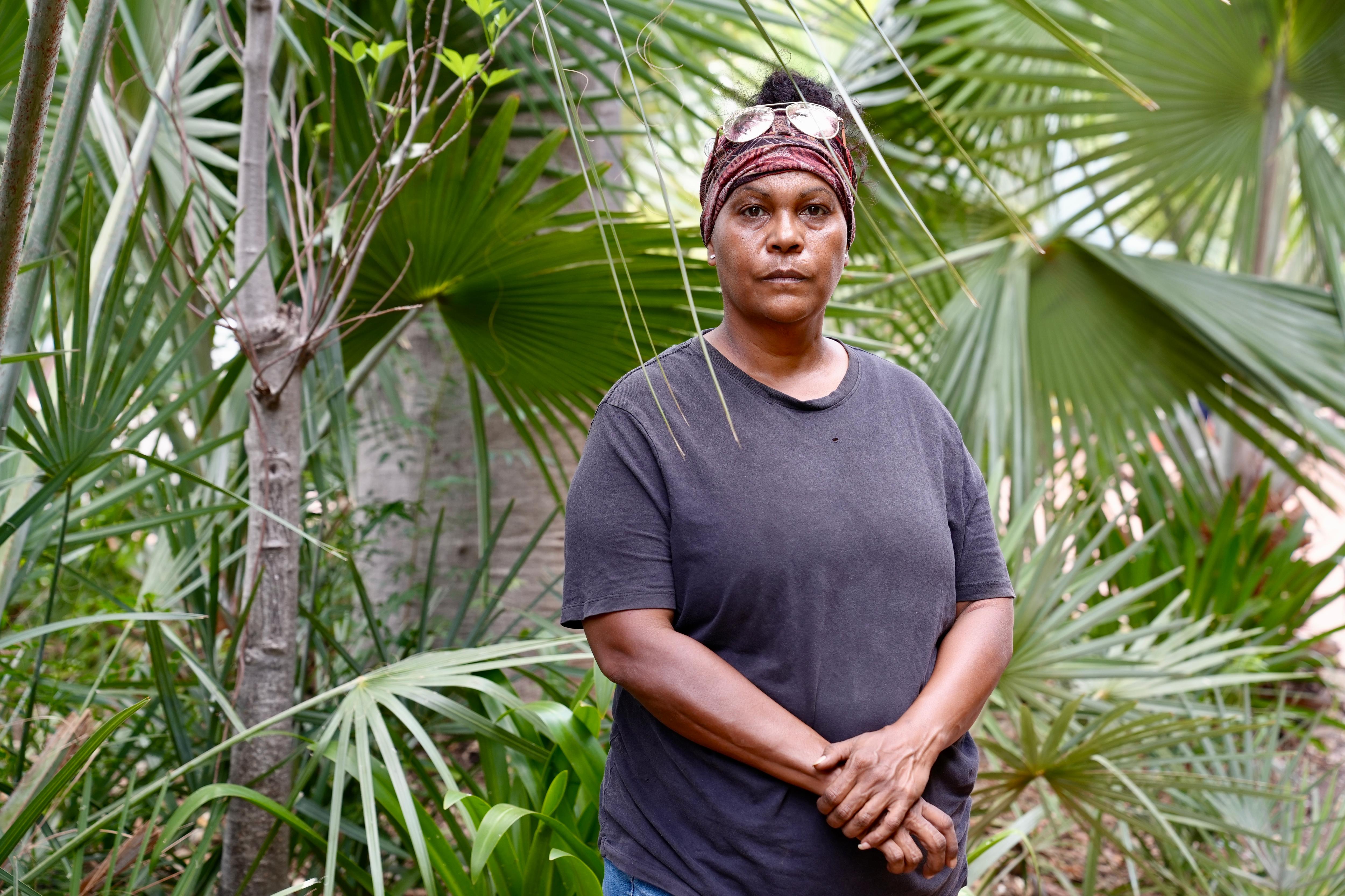Mulher aborígine de meia idade com camisa cinza.