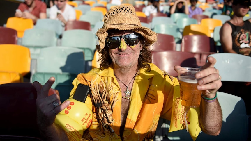 A man enjoys a beer at the cricket