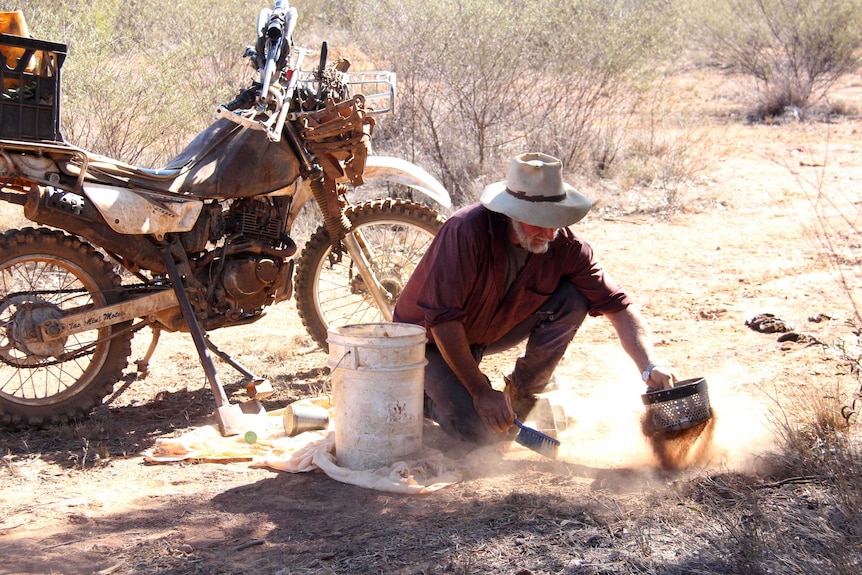 Don Sallway uses a sieve to spread a layer of top soil over one of his traps.