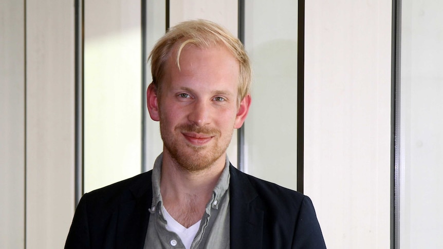 A man in a button up shirt standing in an office.