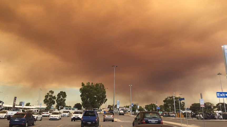 Cloud from a bushfire blanketing the sky above a car park.