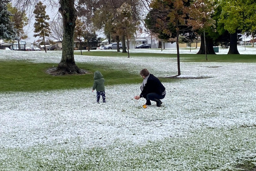 Toddler and woman play in light dusting of snow in park at Ballarat.