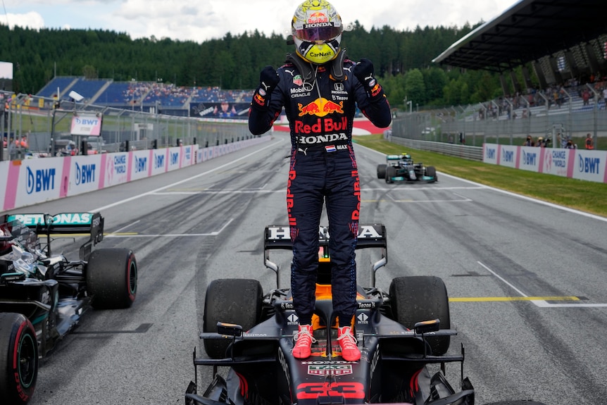 Max Verstappen stands on top of his Formula One car.
