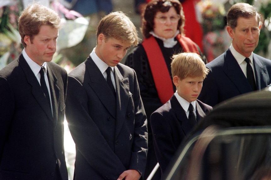 A teenaged Prince William and young Prince Harry with Earl Spencer and their father Prince Charles look towards a hearse