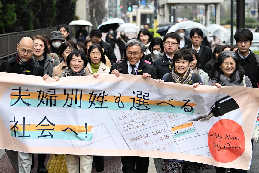 japanese citizens stand with a banner