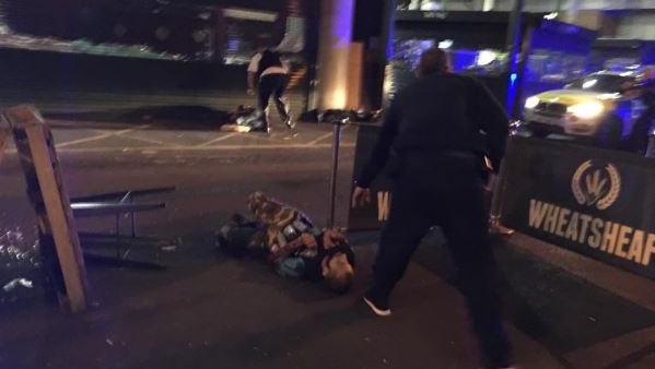 A man with canisters strapped to his body lies on the ground