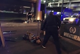 A man with canisters strapped to his body lies on the ground