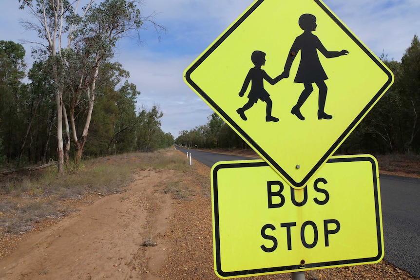 A bright yellow school bus sign on a country road