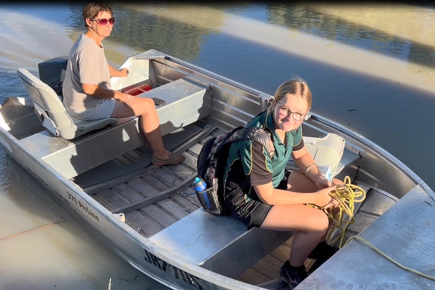 Two people sit in a small metal boat