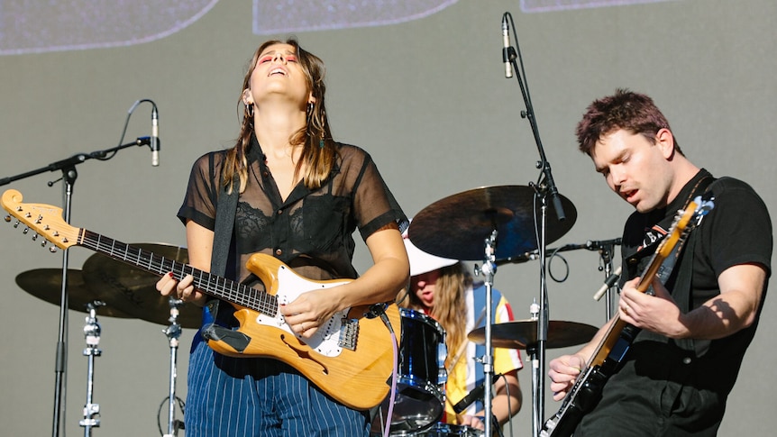 Three members of band Middle Kids performing live on stage