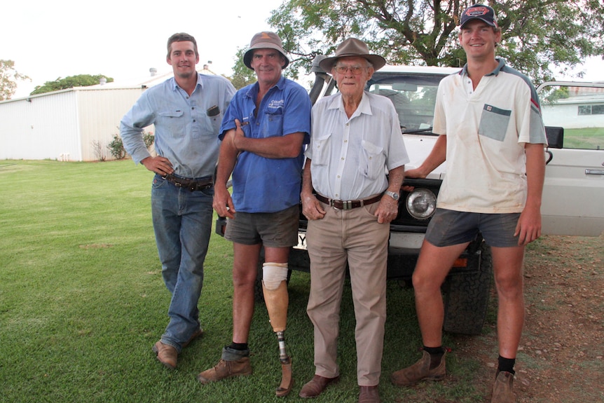 Four men representing three generations of a farming family, lean against the bull-bar of a station vehicle.