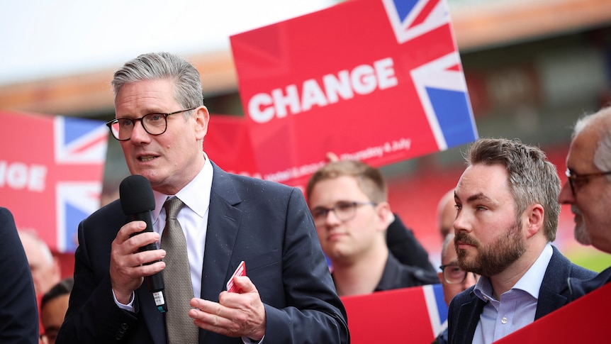 Keir Starmer speaks at a campaign rally as supporters hold red signs behind him that say "change"