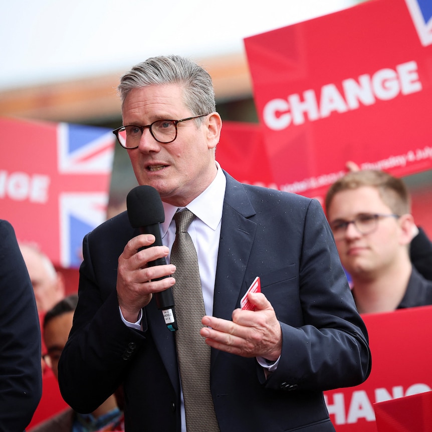 Keir Starmer speaks at a campaign rally as supporters hold red signs behind him that say "change"