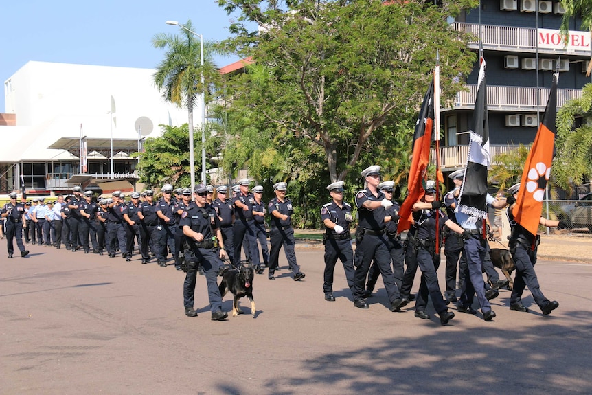 NT Police march through the streets of Darwin behind the Territory flag for Police Remembrance Day.