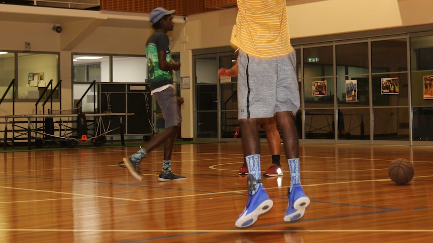 Players wearing ankle trackers shoot hoops with other junior players at the Palmerston and Regional Basketball Association