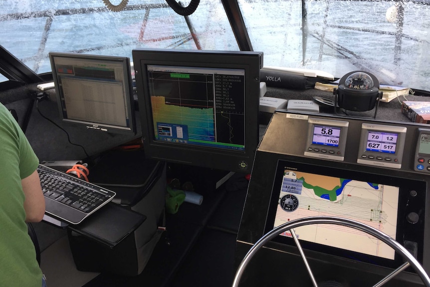 Computers with sonar and maps of seafloor set up in boat.
