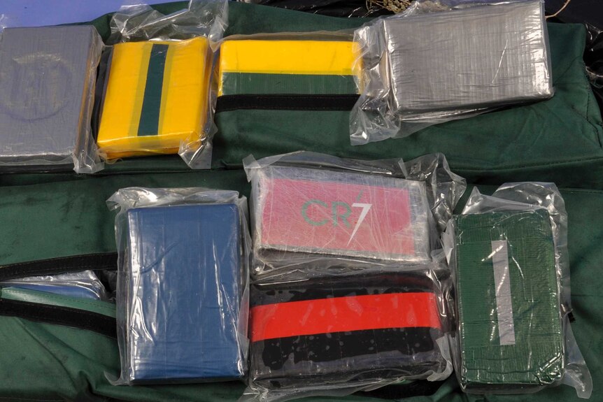 A close-up shot of rectangle blocks wrapped in tape and plastic, allegedly containing drugs.