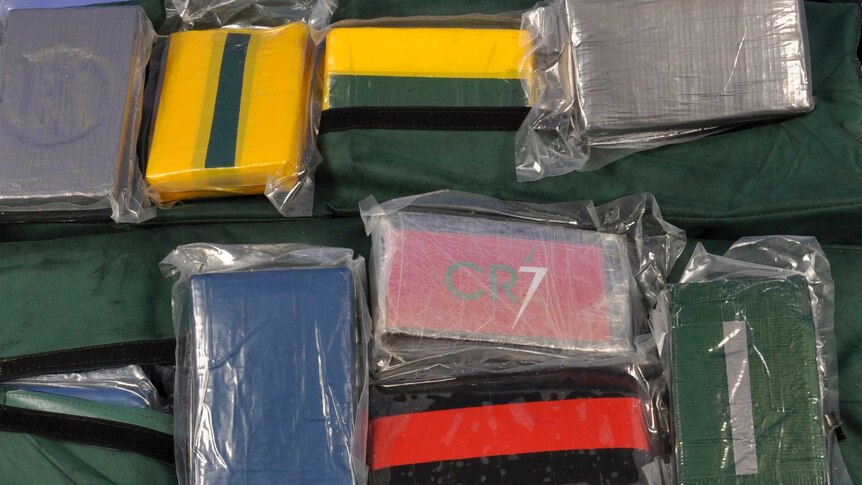 A close-up shot of rectangle blocks wrapped in tape and plastic, allegedly containing drugs.