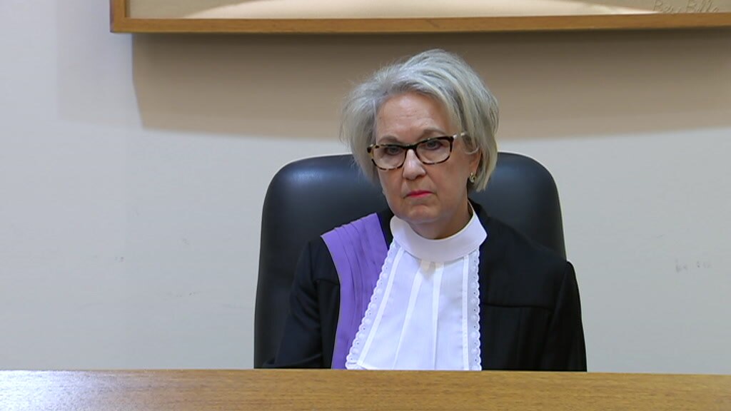 A woman with grey hair and glasses dressed in judicial robes 