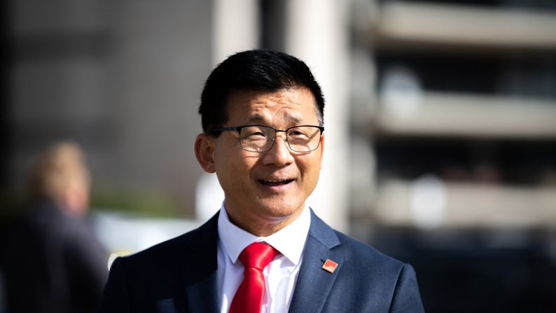 MId shot of Sam Lim wearing glasses and suit with red tie