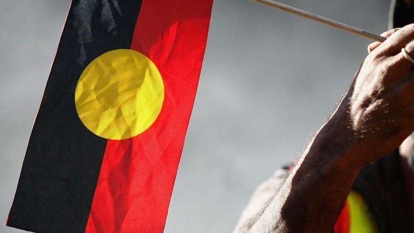 Indigenous Australian holding an Aboriginal flag