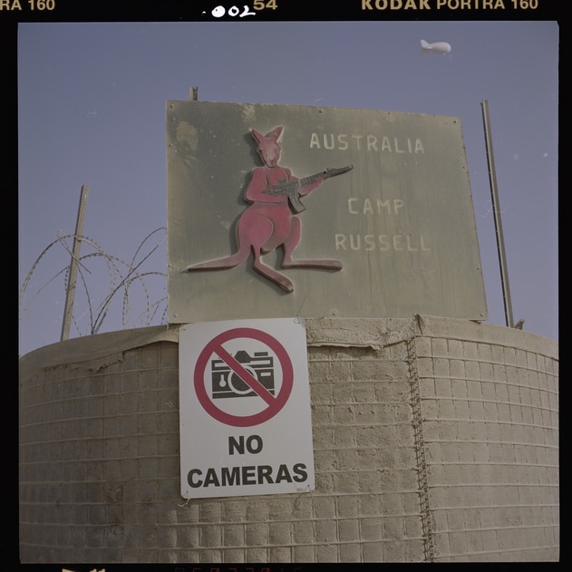 A negative of a photograph shows a sign outside an Army base in Afghanistan. It has a kangaroo on it.