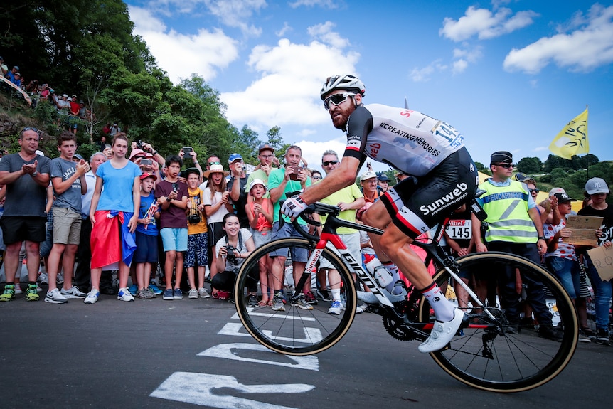 German cyclist Simon Geschke rides his bike past a large crowd 