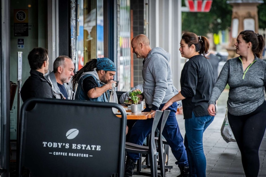 Patrons sit outside a busy cafe in Sydney.