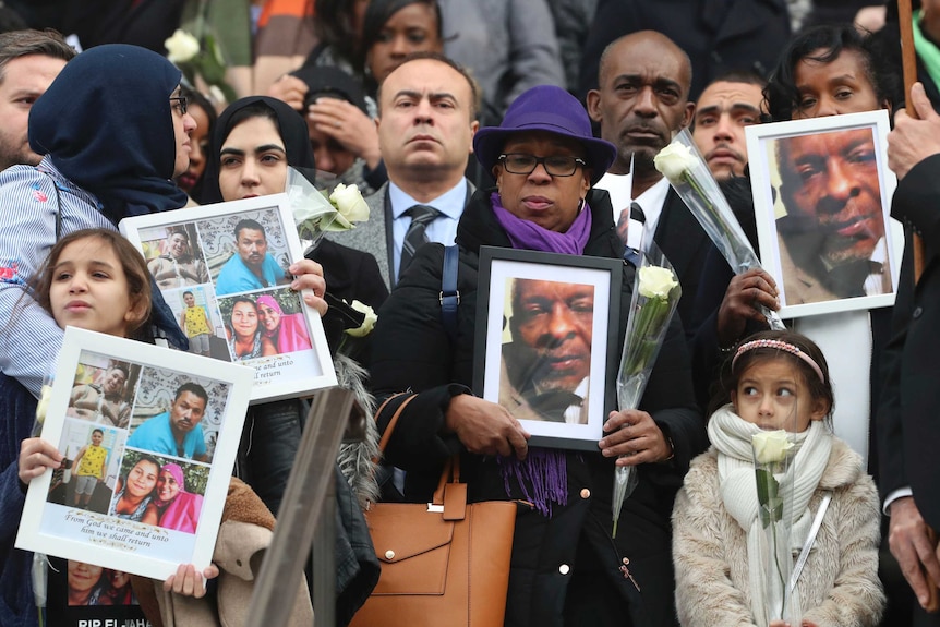 People hold up photos of their loved ones, victims of the fire.