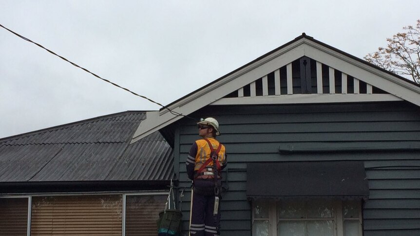 An Energex employee at work trying to restore power to Fernvale homes and businesses