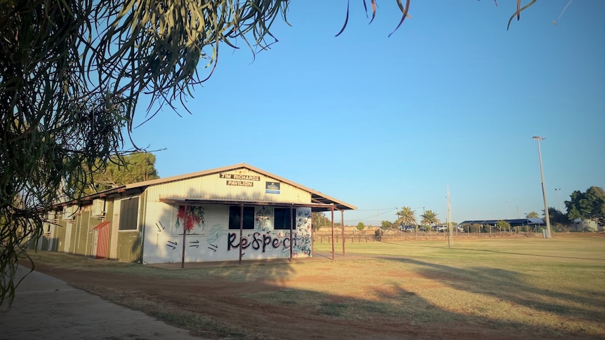 A pavilion next to grass with the word "respect" painted on the wall. 