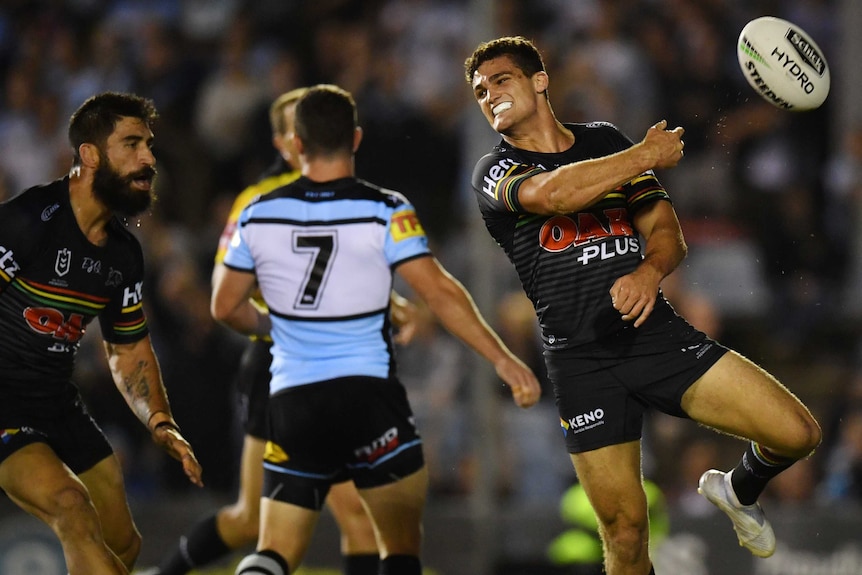 Nathan Cleary smiles as he throws the ball in the air with his right hand after scoring a try for Penrith.