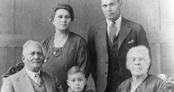 Black and white family portrait of elderly couple with younger man and woman and young boy.