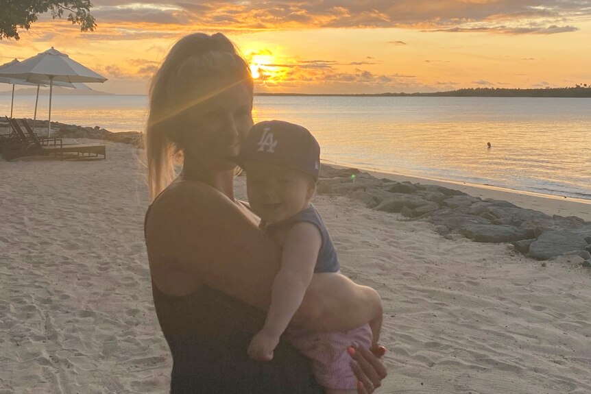 Woman with baby and sunset and beach in background