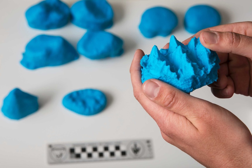 Hands hold 3D print of a complex tooth