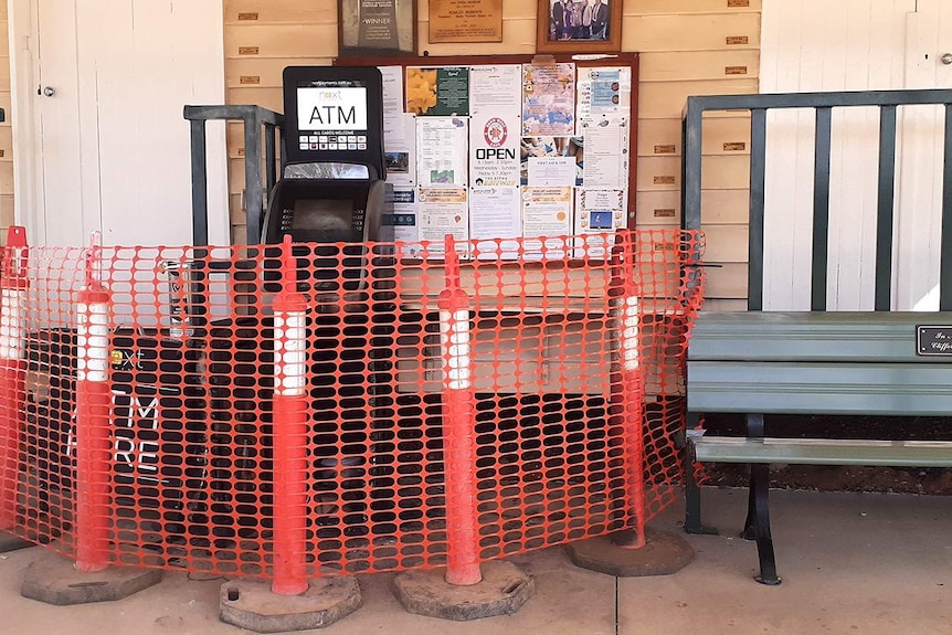 A temporary orange barricade erected around a blackened, destroyed ATM.