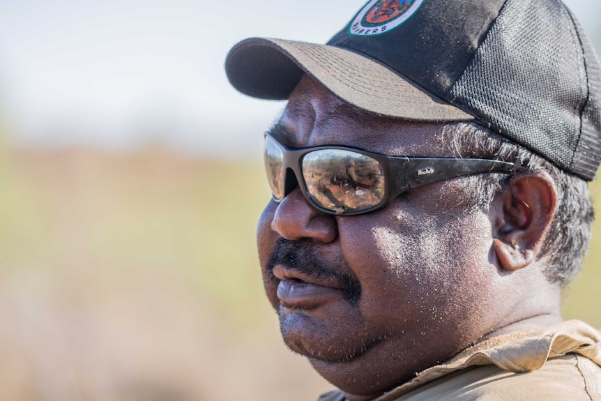 Close up of an Indigenous man wearing a cap and sunglasses.