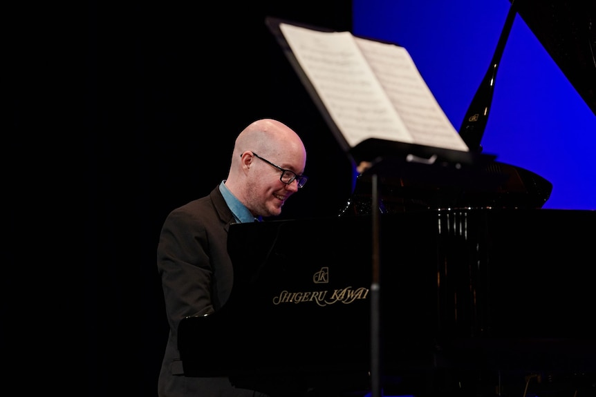 Leigh Harrold plays a grand piano. There is a music stand with music in front of the piano.