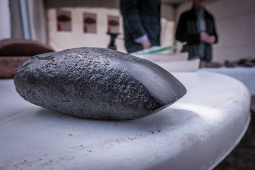 A black rock with a point on the end sits on a table.