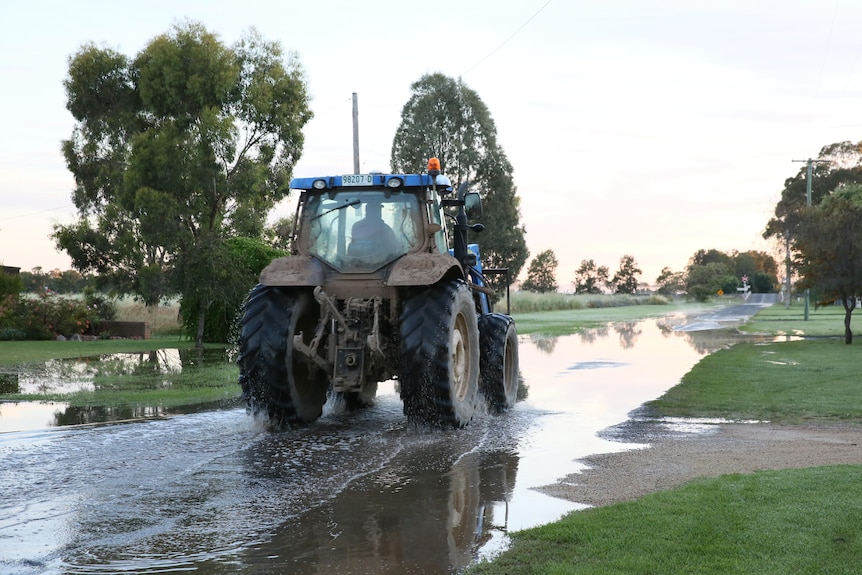 Tractor drives through water over the road