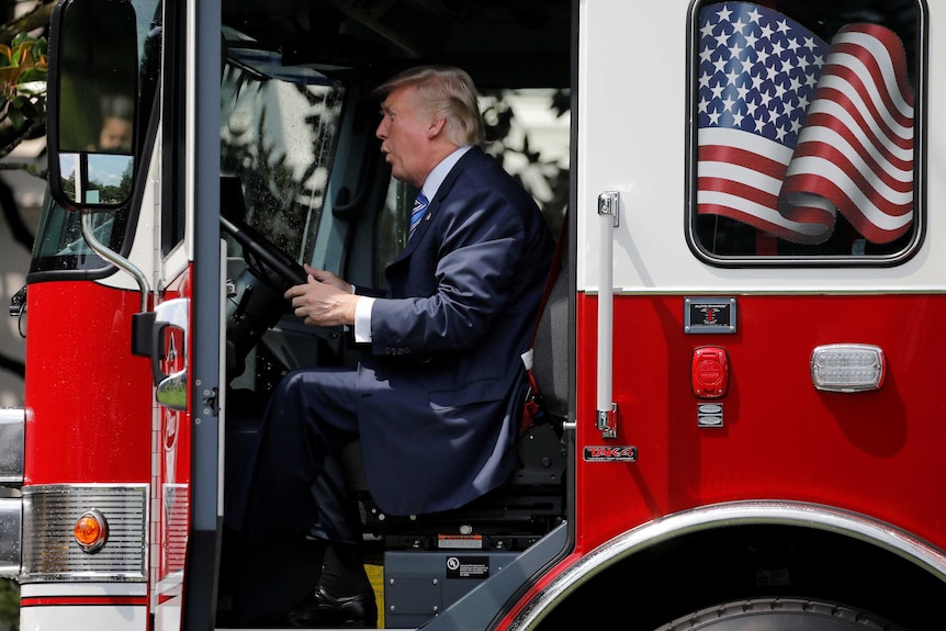 US President Donald Trump sits on a firefighter truck.