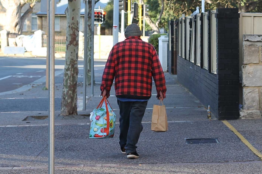 man walking down the street with bags