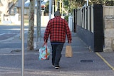 A man walking down the street with bags.