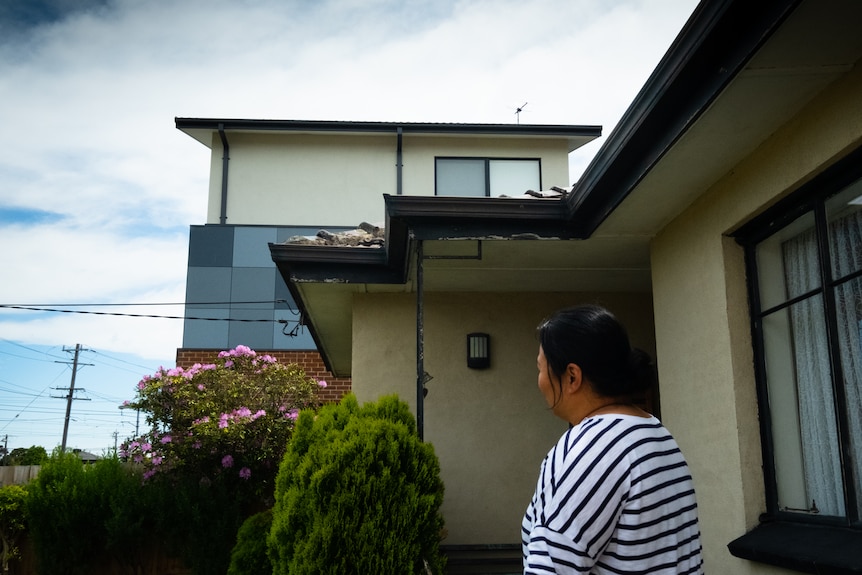 A woman looks at a building facade jutting out.