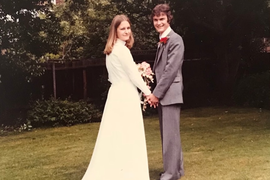 A young bride and groom holding hands in a park